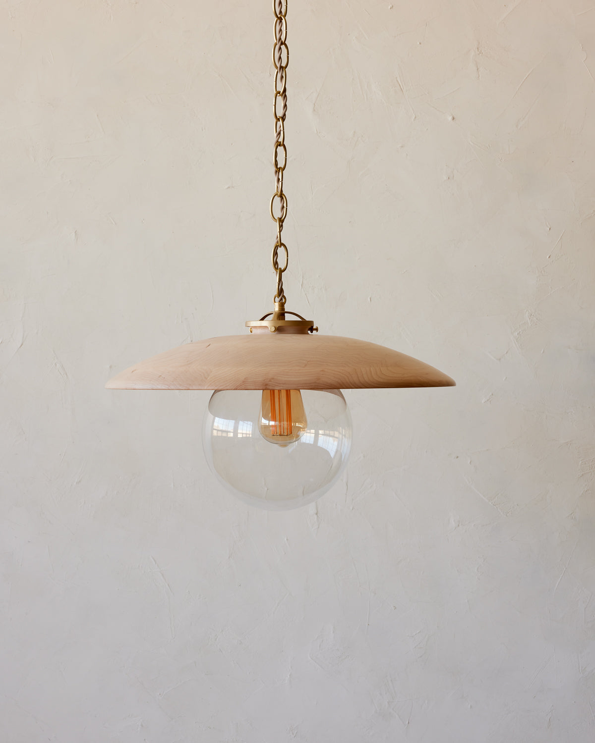 Large pendant light with oversized clear glass globe and decorative wooden clear maple shade with brass chain