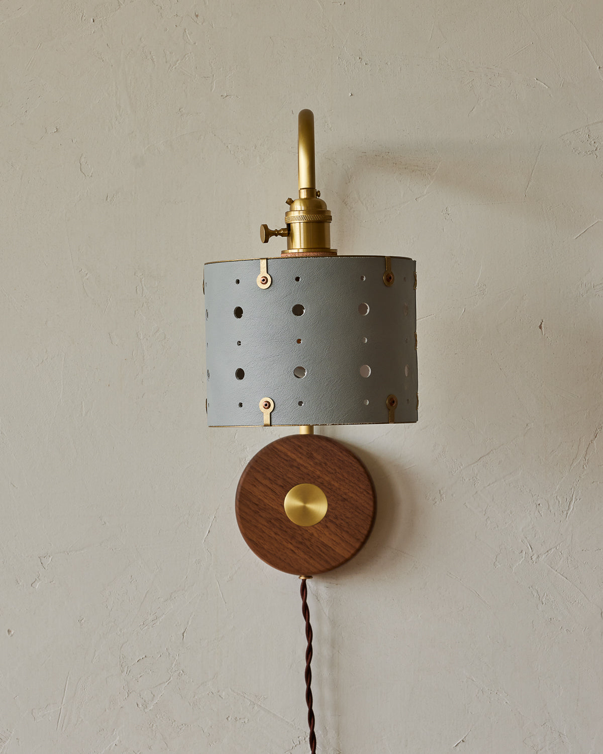 Articulating satin brass sconce with blue handstitched shade and walnut backplate #leather-finish_cloud blue #wiring_plug-in
