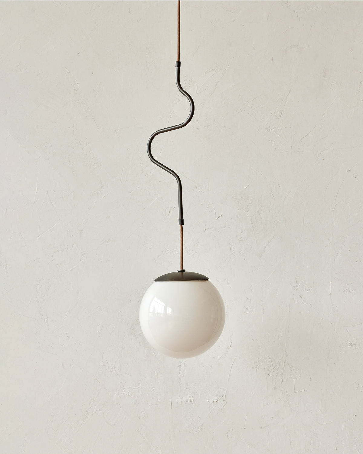 Modern black globe pendant light with dark oil rubbed brass curved body and white milk glass globe