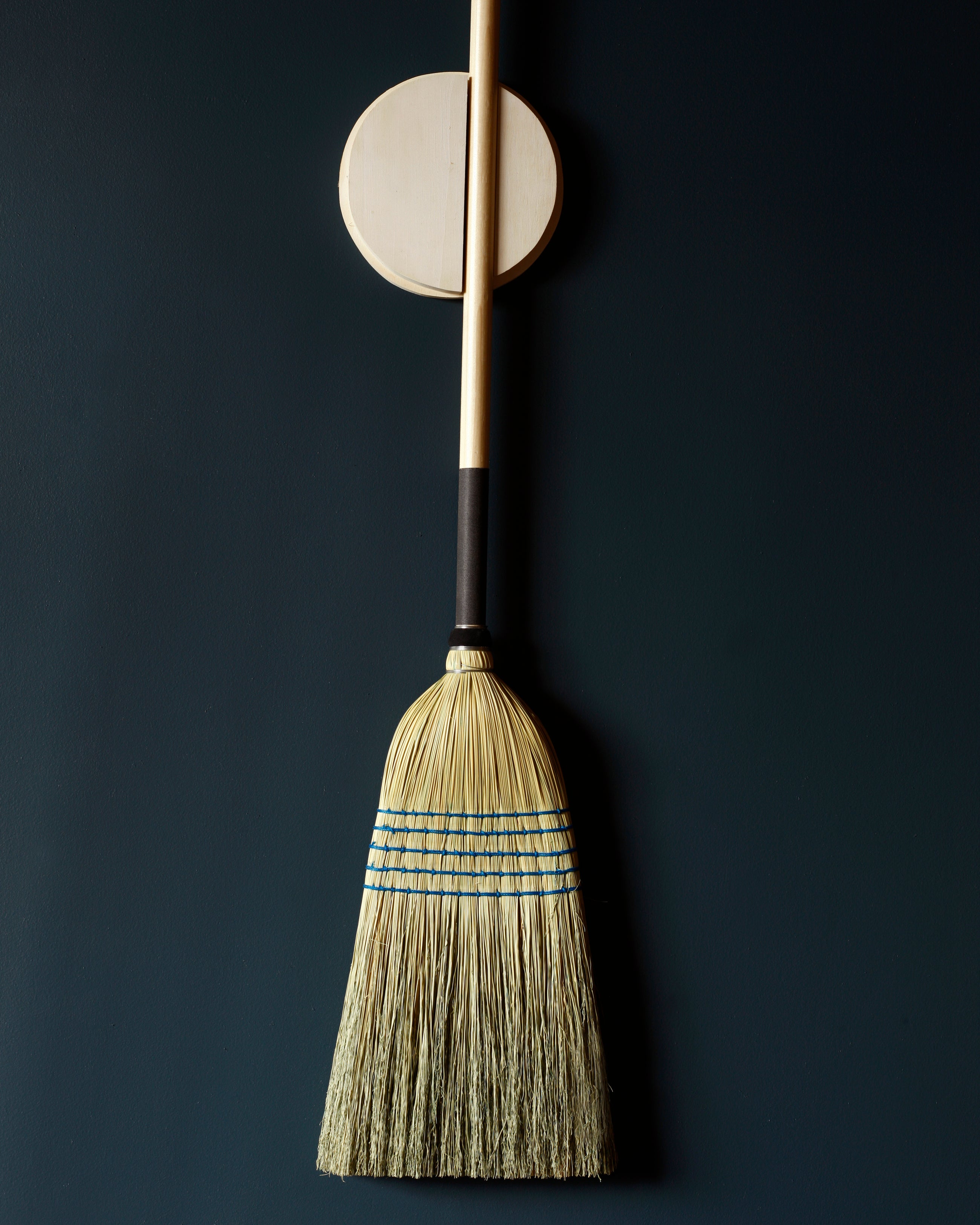 Natural broom hanging on a wall with a  holder 