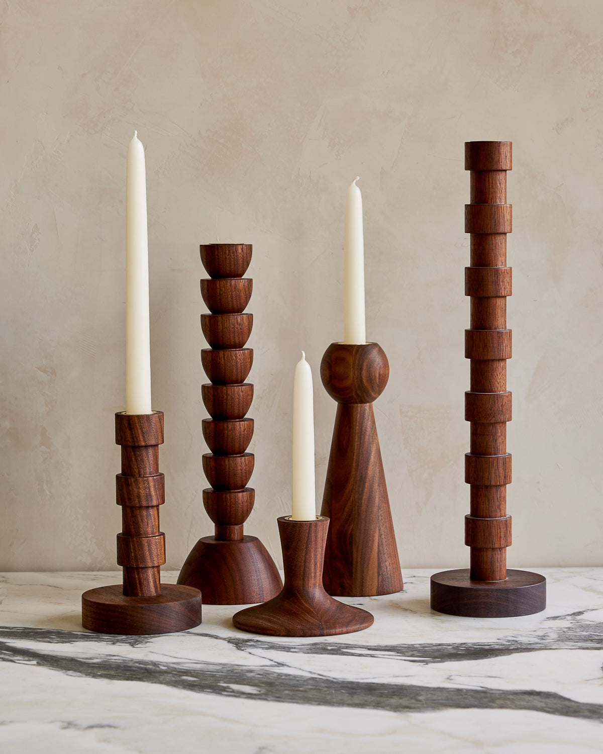 Collection of black walnut candle holders with stark white taper candles