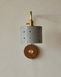 Articulating satin brass sconce with blue handstitched leather shade and walnut backplate