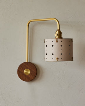 Articulating satin brass wall sconce with white handstitched shade and walnut backplate