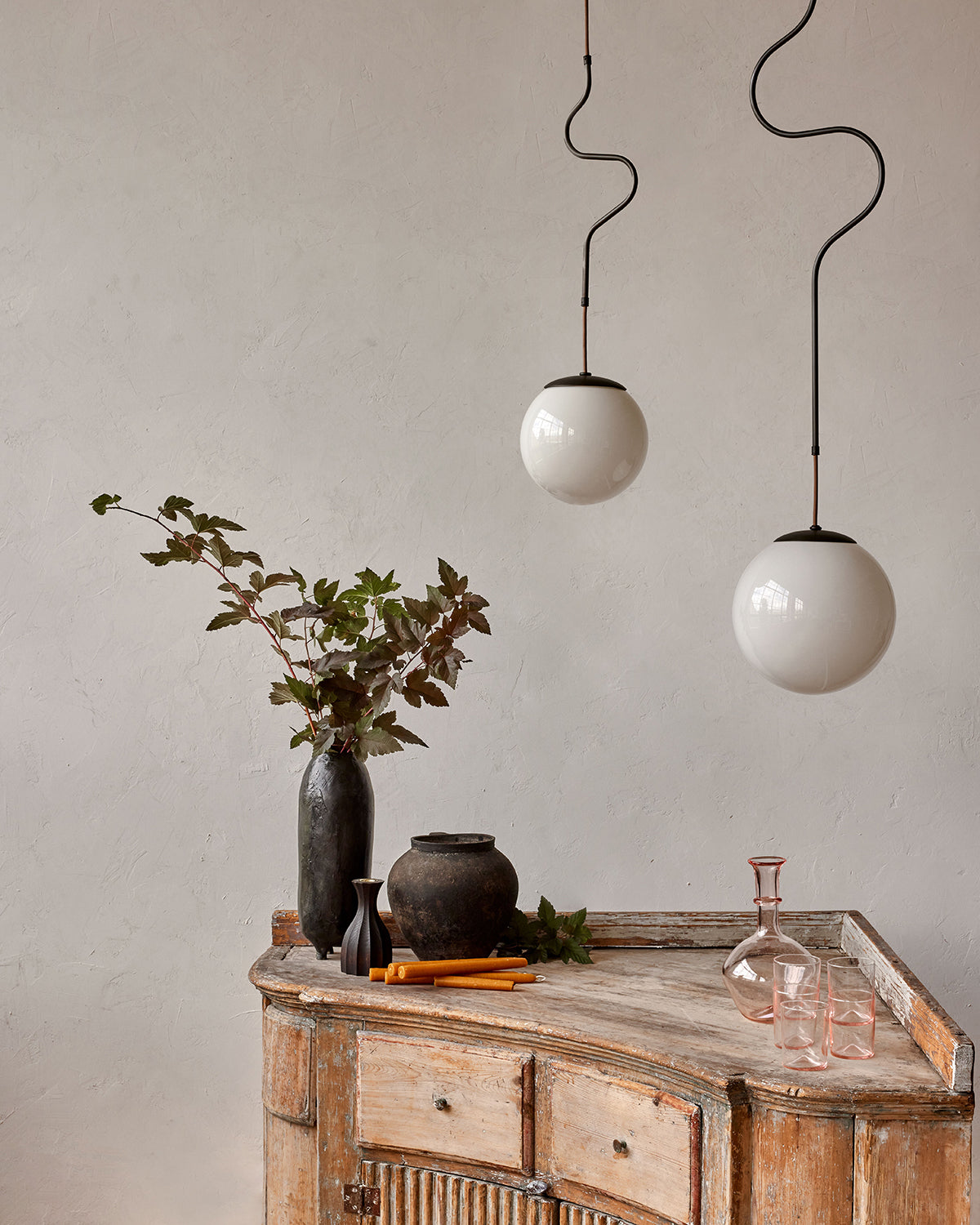 Modern black globe pendant light with dark oil rubbed brass curved body and white milk glass globe over bar counter