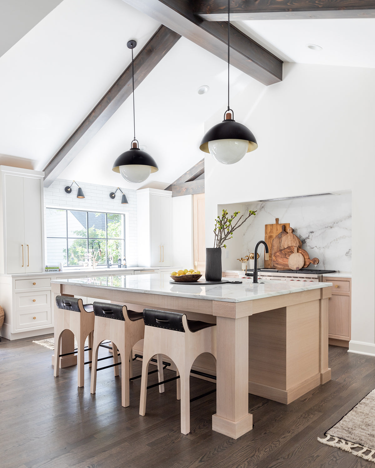 Black leather Jack counter stools from Lostine at a kitchen island in large white kitchen with vaulted ceiling.