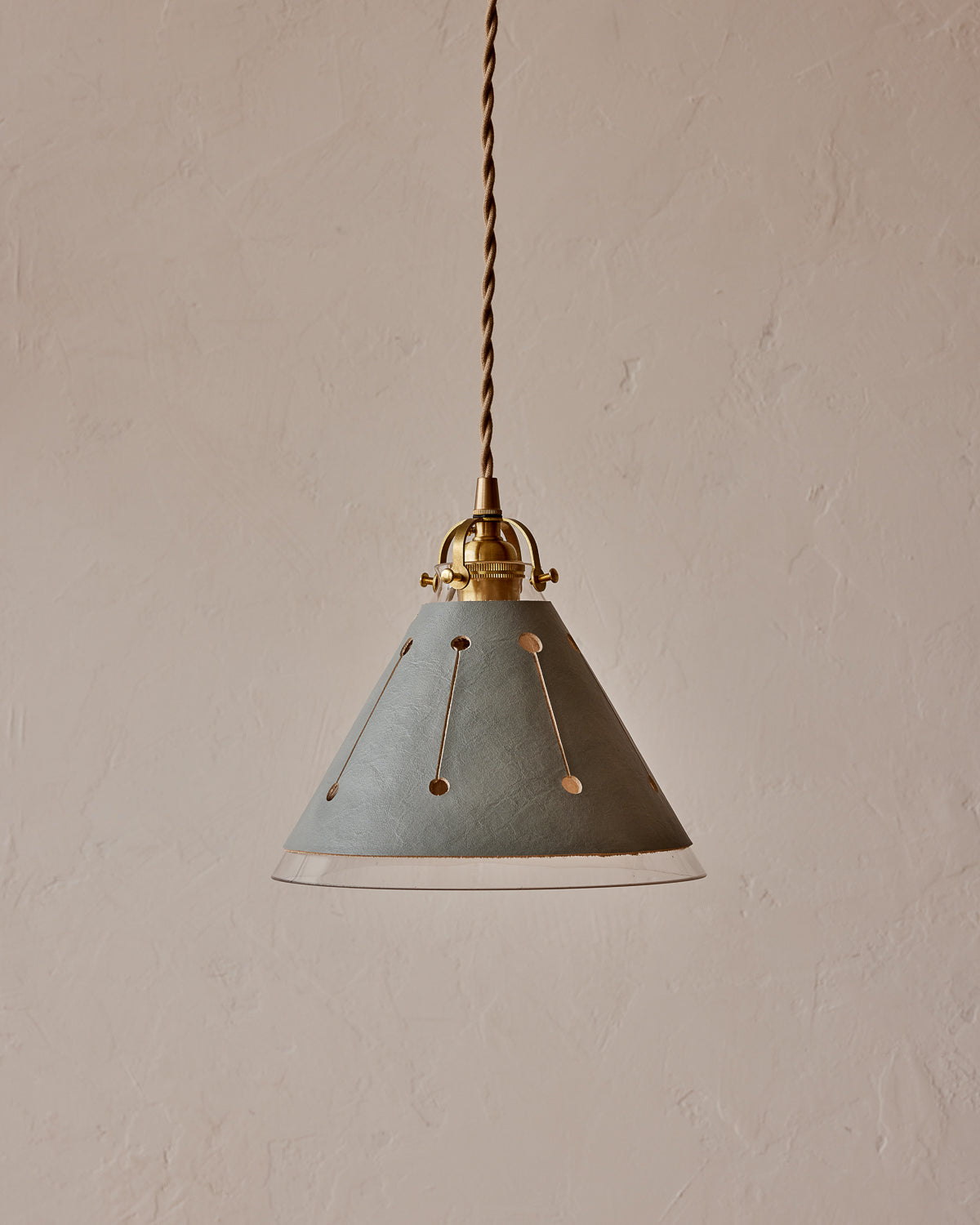A pendant light with a blue leather sleeve and a conical glass shade, featuring brass fitter and twisted cloth cord.   #leather-finish_cloud blue