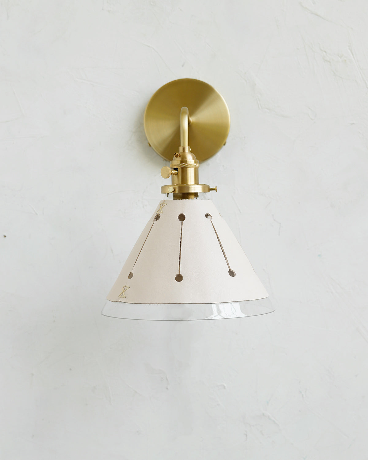 Classic satin brass wall sconce with cone glass diffuser and decorative handstitched leather shade