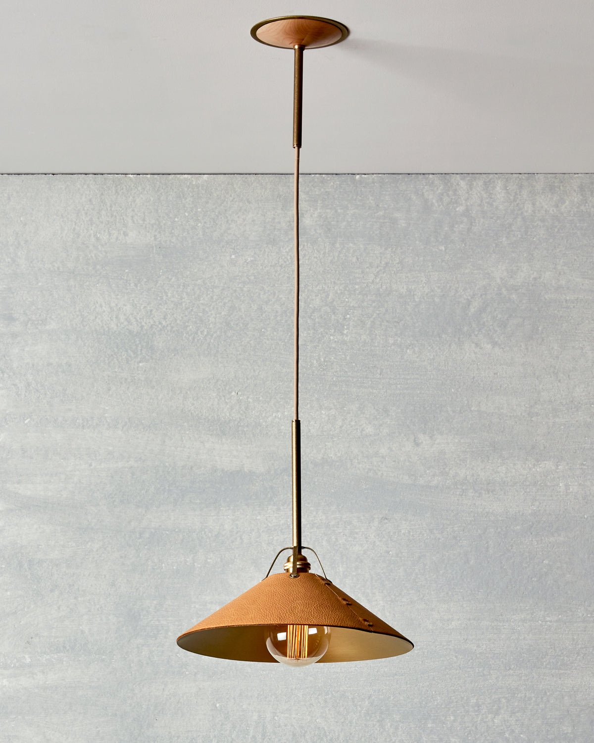 Natural tan leather and brass ceiling pendant light. Made by RTO Lighting in Philadelphia. Hardwired light fixture. Simple interior design, made in the USA.