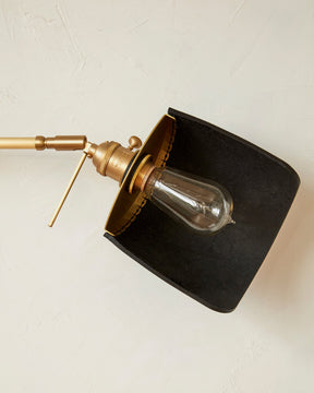 Curved black leather and brass shade for articulating wall sconce