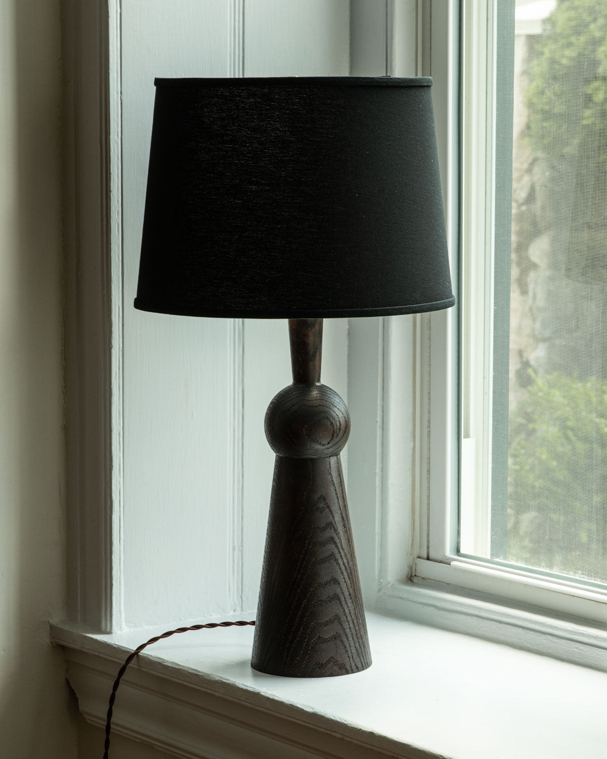 Dark wash solid wood table lamp with gently tapered body and black linen shade