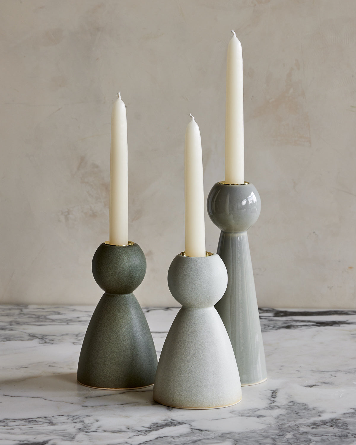 Collection of blue and green ceramic candle holders of various styles and glazes with white taper candles