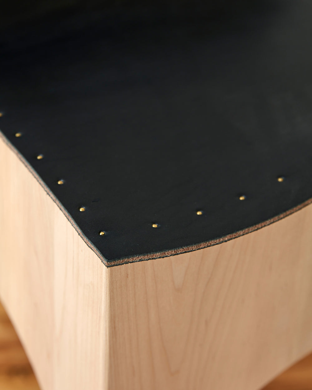 Brass nails of Sculpted stool with black leather and maple wooden base with metal foot rest and short backrest. Counter and bar height. Handmade in Philadelphia by Lostine. Simple Interior Design. Warm American Modern Design #leather-finish_black harness