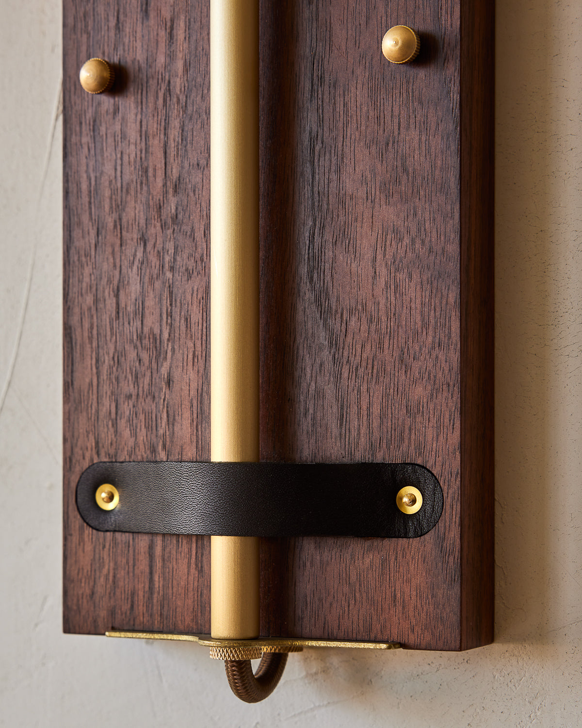 Black walnut wooden wall sconce with articulating brass arm and black leather