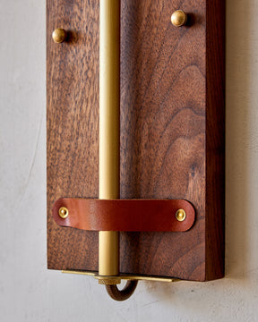 Black walnut wooden wall sconce with articulating brass arm and tan leather