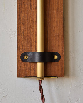 Black walnut wooden plug in wall sconce with articulating brass arm and black leather