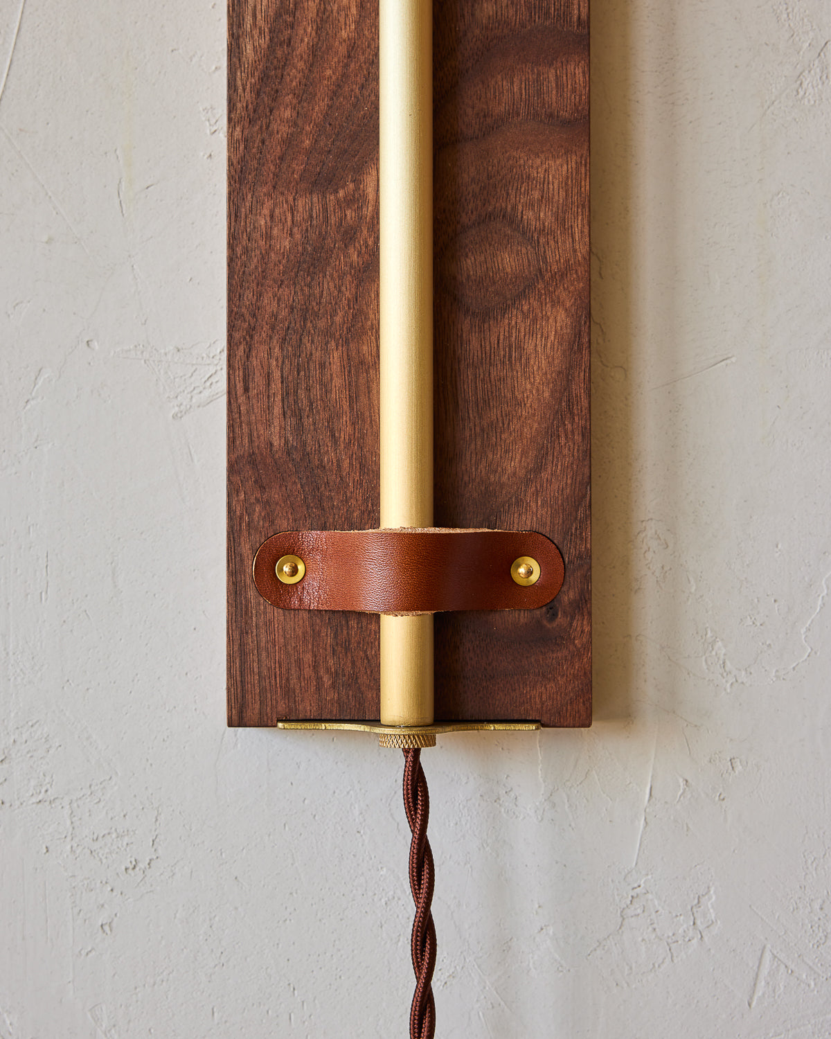 Black walnut wooden wall sconce with articulating brass arm and tan leather
