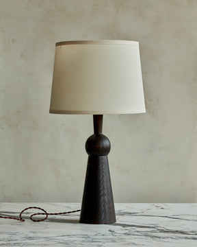 Dark wash solid wood table lamp with gently tapered body and ivory linen shade
