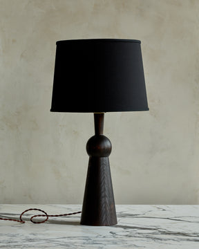 Dark wash solid wood table lamp with gently tapered body and black linen shade