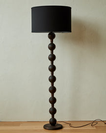 Tall sculptural solid wood floor lamp with barbell design in dark wash finish with black linen drum shade