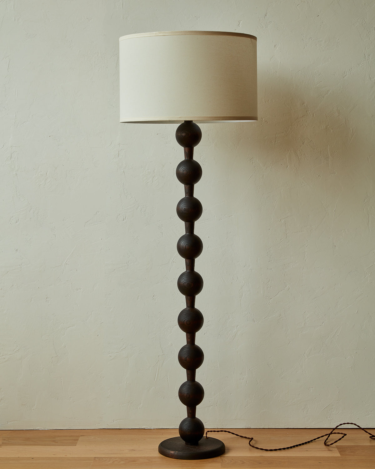 Tall sculptural solid wood floor lamp with barbell design in dark wash finish with white linen drum shade