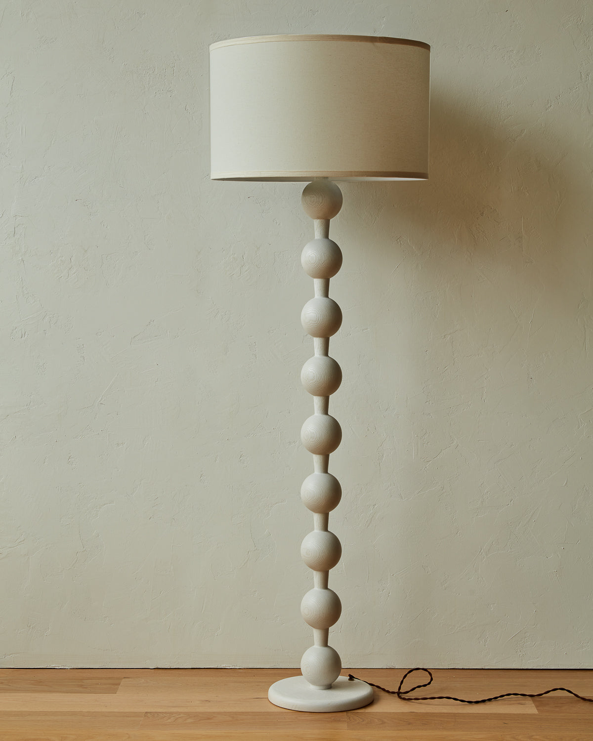 Tall sculptural solid red oak floor lamp with barbell design in white wash finish with ivory linen drum shade
#color_white wash red oak
#shade-color_ivory linen
