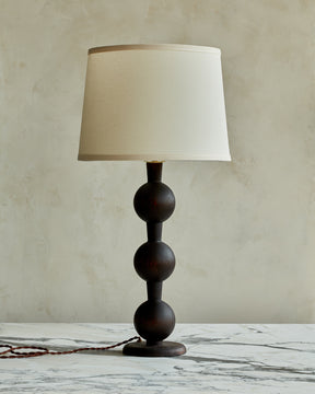 Sculptural solid wood table lamp with barbell design in dark wash finish with ivory linen shade