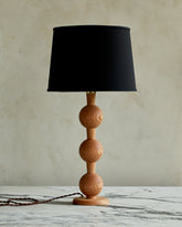 Sculptural solid wood table lamp with barbell design in natural finish with black linen shade