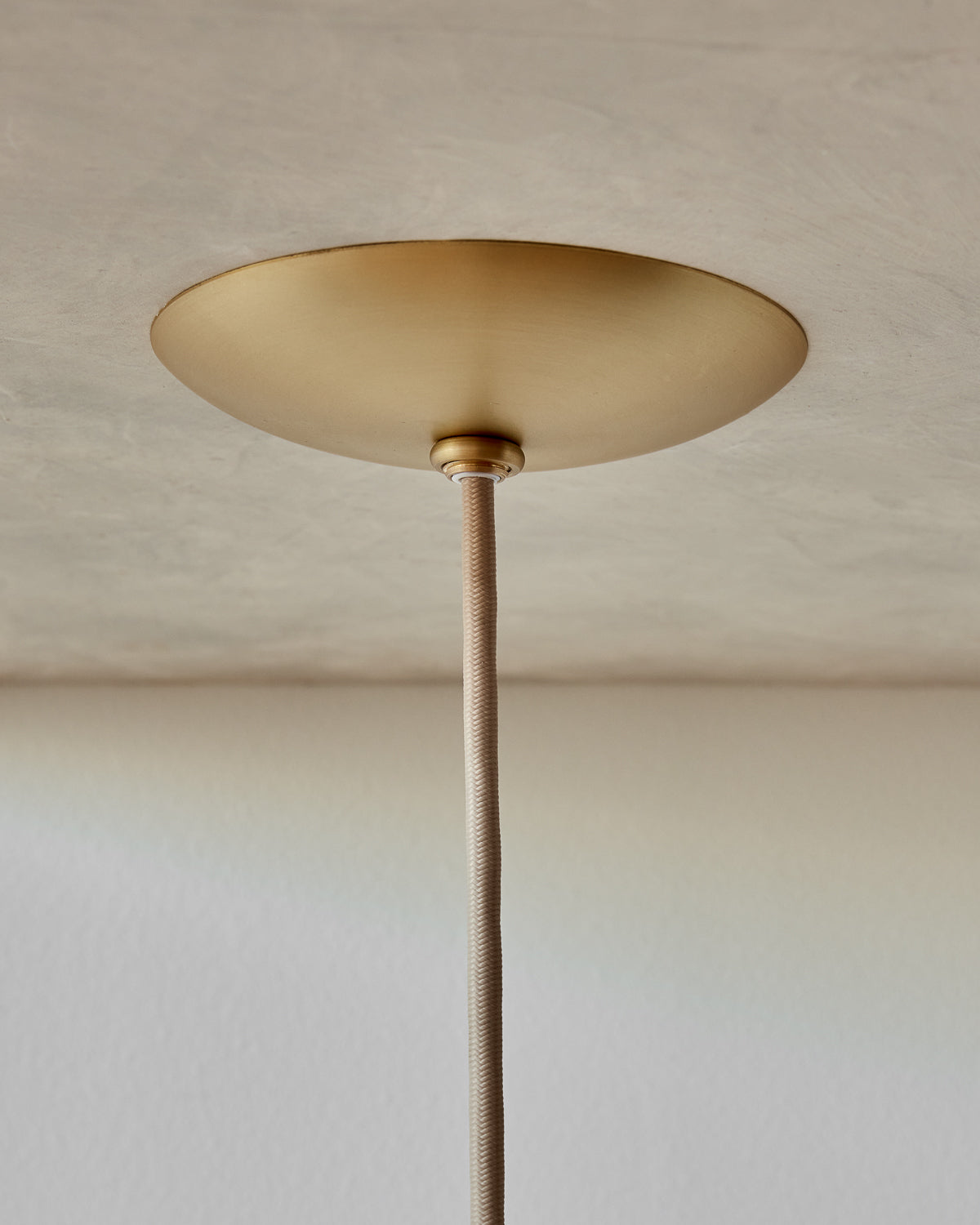 Modern brass globe pendant light with warm satin brass curved body and white milk glass globe