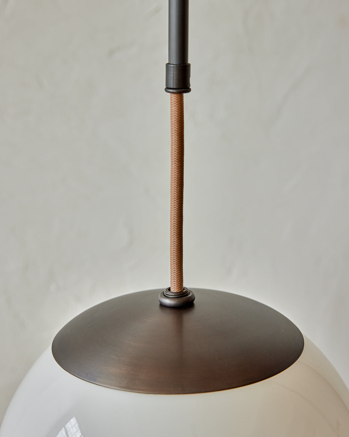Modern black globe pendant light with dark oil rubbed brass curved body and white milk glass globe