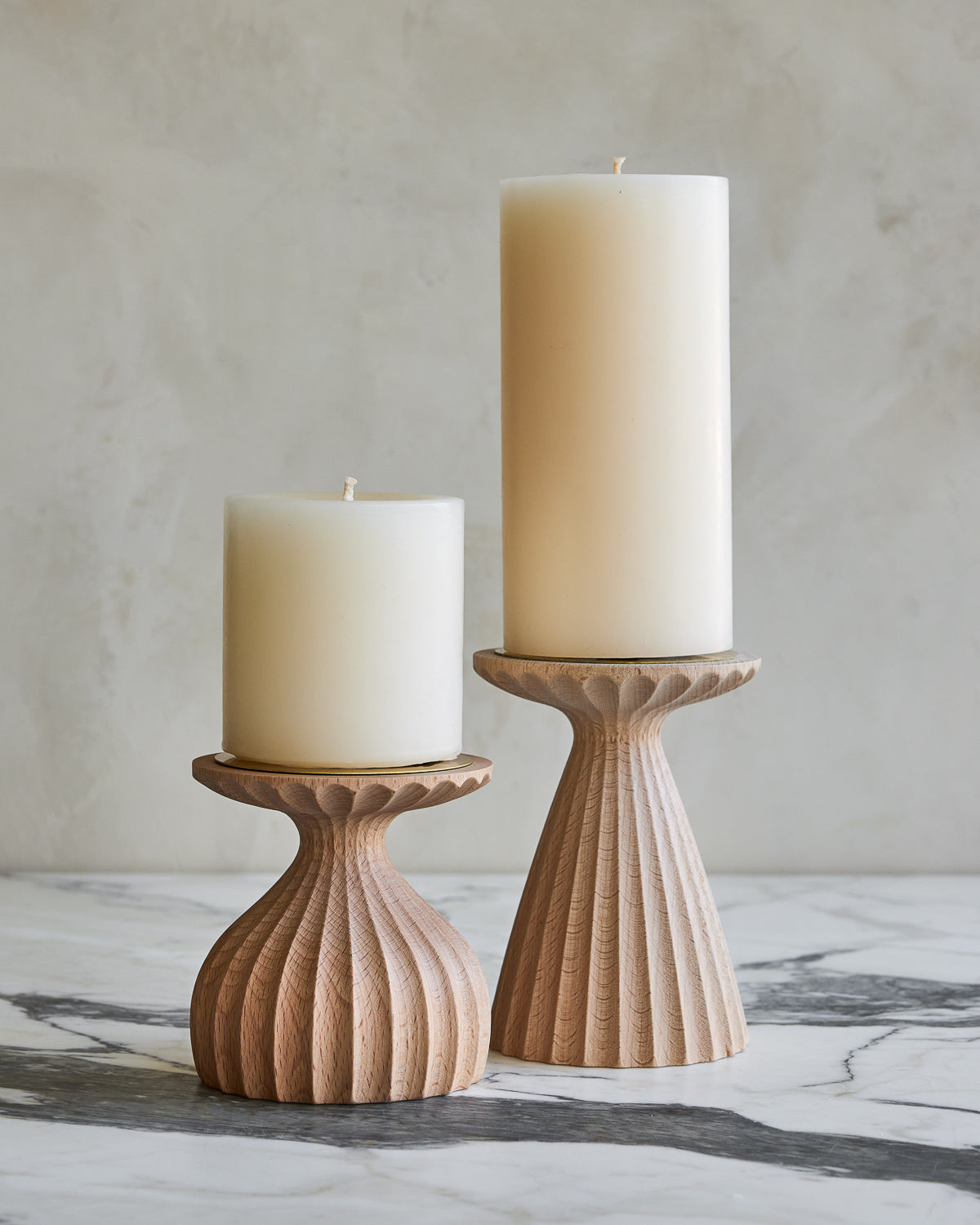 Pair of delicately grooved pillar candle holders in natural maple wood with shell white pillar candles