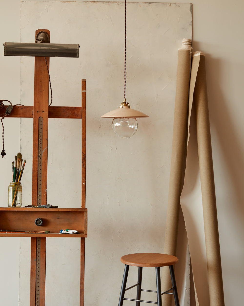 Pendant light with large clear glass globe and decorative wooden clear maple shade hanging in art studio. Made by Lostine in Philadelphia. Simple interior design, made in the USA. Warm American Modern Design #shade-finish_clear maple #Cord-Color---Glass_Brown Cord - Clear Globe