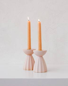 Blush Sabine ceramic candle holder with fluted ridged base in matte pink glaze with orange taper candles