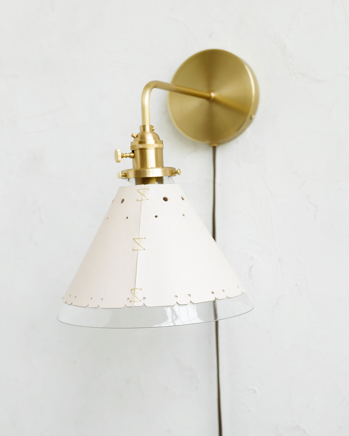 Classic satin brass plug in wall sconce with cone glass diffuser and decorative handstitched leather shade