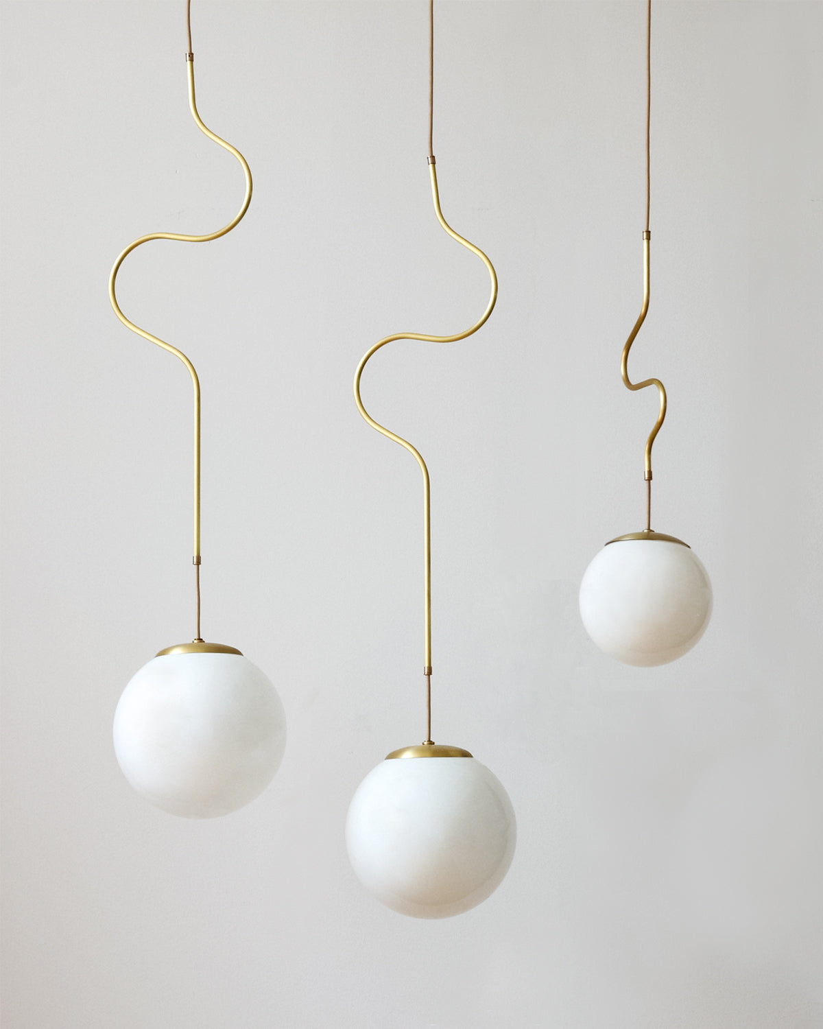 Satin brass Contour ceiling pendant lights made by Lostine in Philadelphia, Pennsylvania.  Satin brass modern lighting design with white glass globe.  Hardwired light fixture.  Simple interior design, made in the USA.